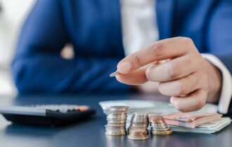 Man in pak telt munten naast rekenmachine en briefgeld als symbool voor financieringsbegroting